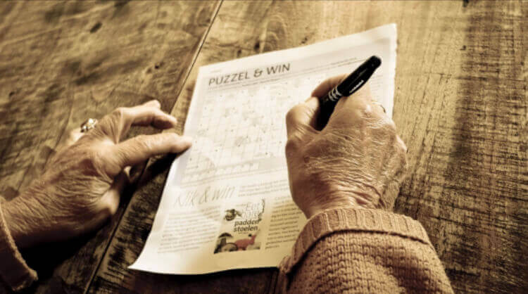 an elderly man doing a Crossword puzzle