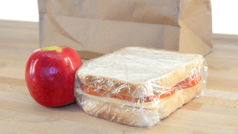 a sandwich and an apple beside a brown paper bag