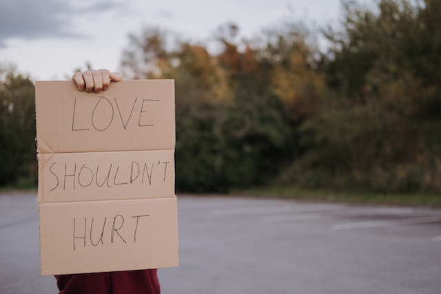 A man with a sign that says love shouldn't hurt