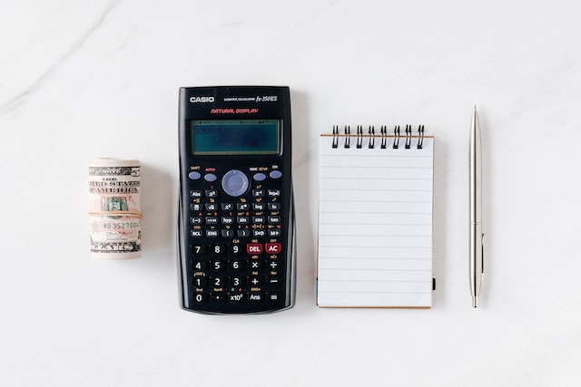 A Calculator and a jar filled with dollar bills and coins