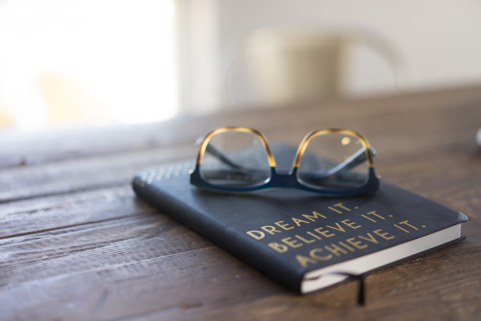Black and brown eyeglasses on a book on a wooden table