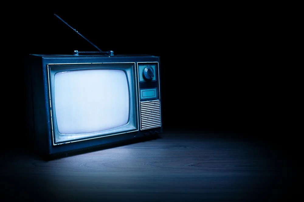 An old turned off TV set in a dark and empty room