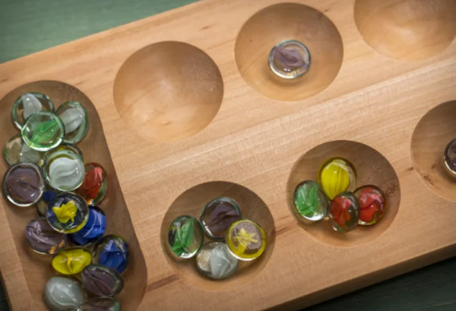 A mancala game board set on top of a table in a game room