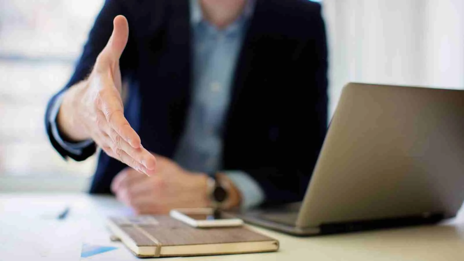 Two business professionals shaking hands, symbolizing cooperative negotiations in Canada and competitive negotiations in the USA.