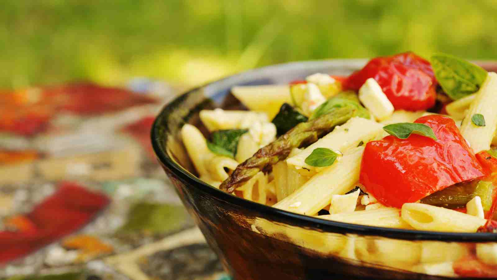 A bowl of roasted vegetable medley pasta on top of a kitchen table