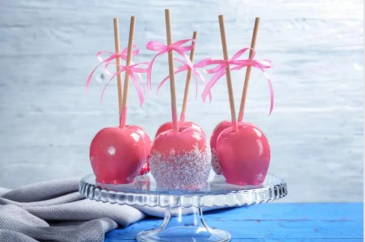 Prepared candy apples in a variety of colors on a plate on a kitchen table